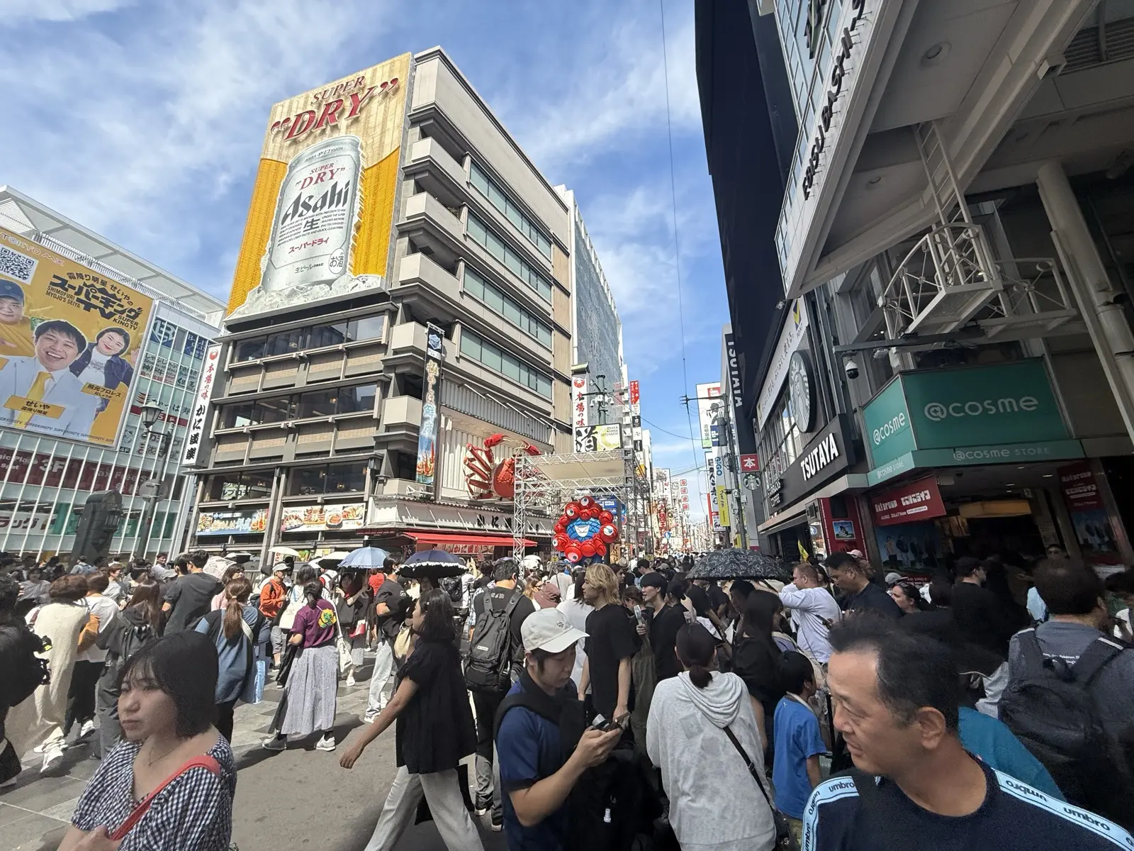 The packed main street of Dotonbori in Osaka under the giant Asahi Super Dry billboard and the moving crab sign, shoulder-to-shoulder crowds