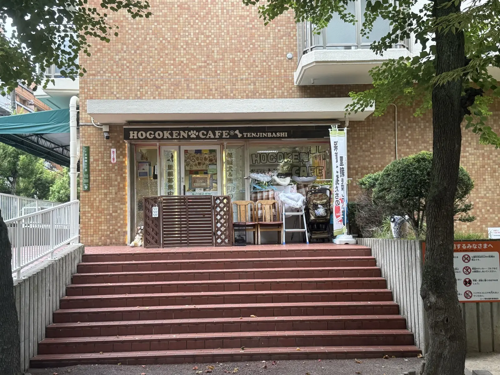 The brick-building storefront of HOGOKEN CAFE Tenjinbashi, with a sign reading HOGOKEN CAFE Tenjinbashi above the entrance and steps leading up