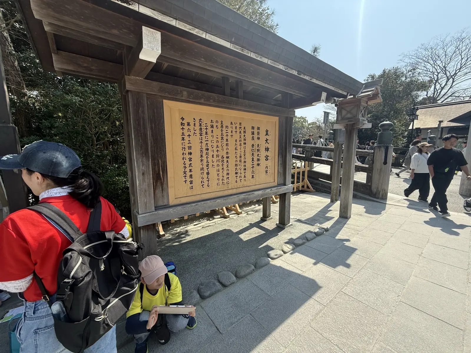 A wooden information board reading Kotai Jingu (the formal name of the Naiku Inner Shrine) at Ise Jingu, with visitors reading it