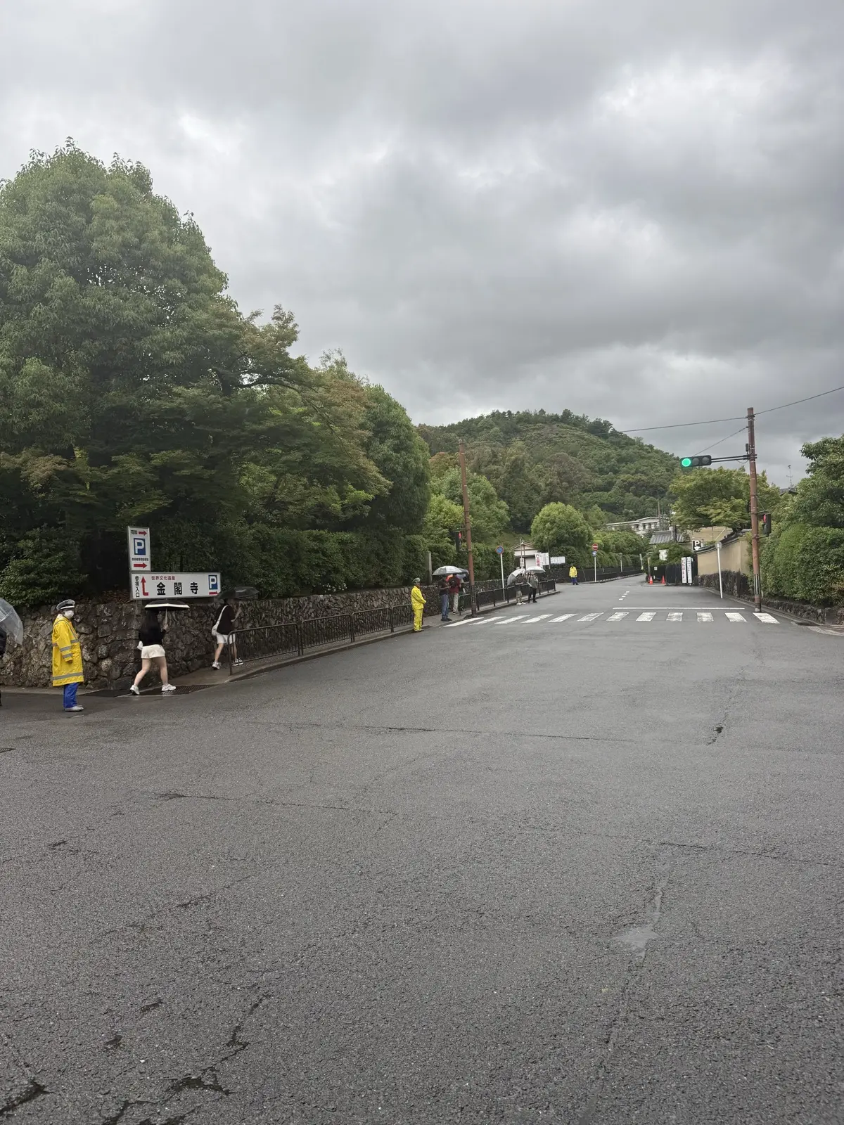 The approach road to Kinkaku-ji with the temple parking sign on a rainy day — our own photo