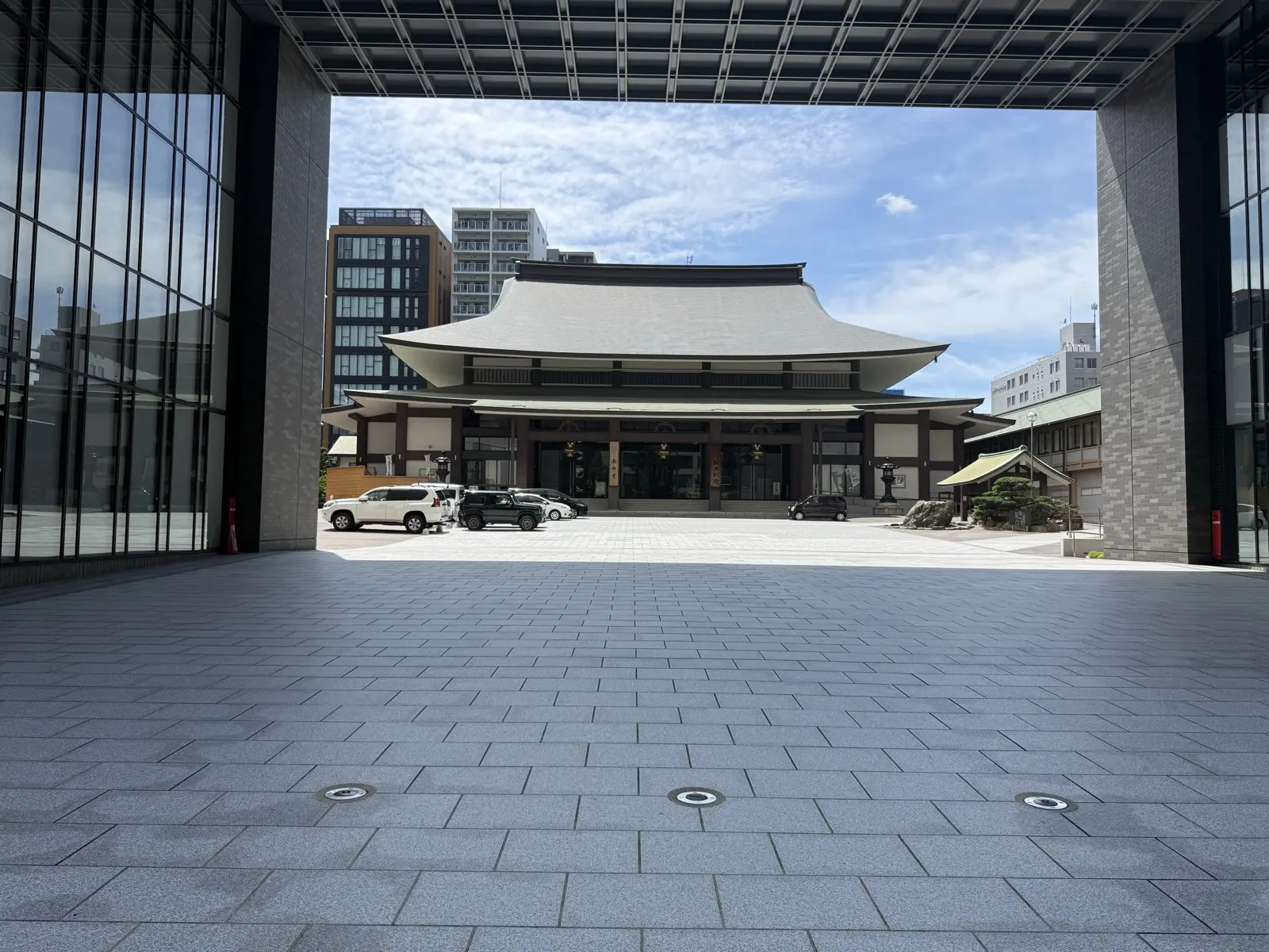 The Kita-Mido Buddhist temple hall on Midosuji in Osaka, its sweeping tiled roof framed by the glass gate of a modern building