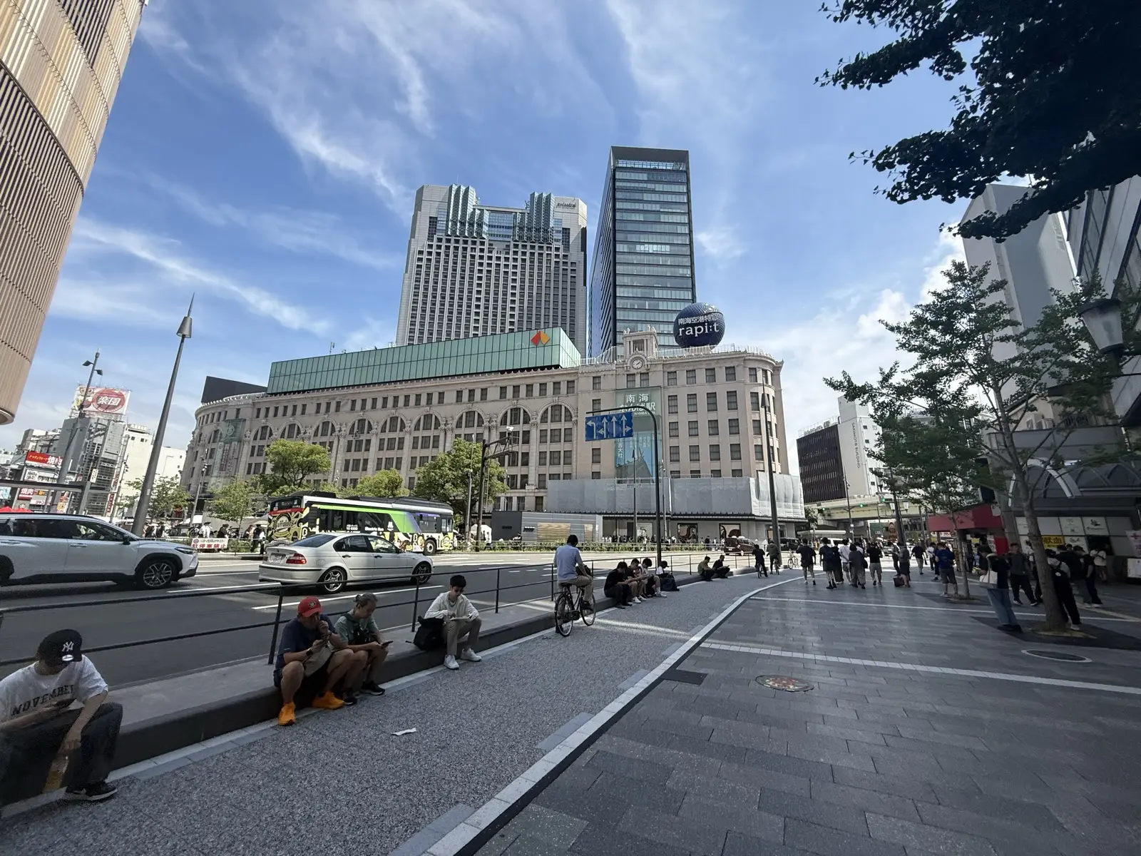 The grand arched Art-Deco Nankai Building housing Takashimaya and Nankai Namba Station, with the wide open Namba plaza and people resting on the steps
