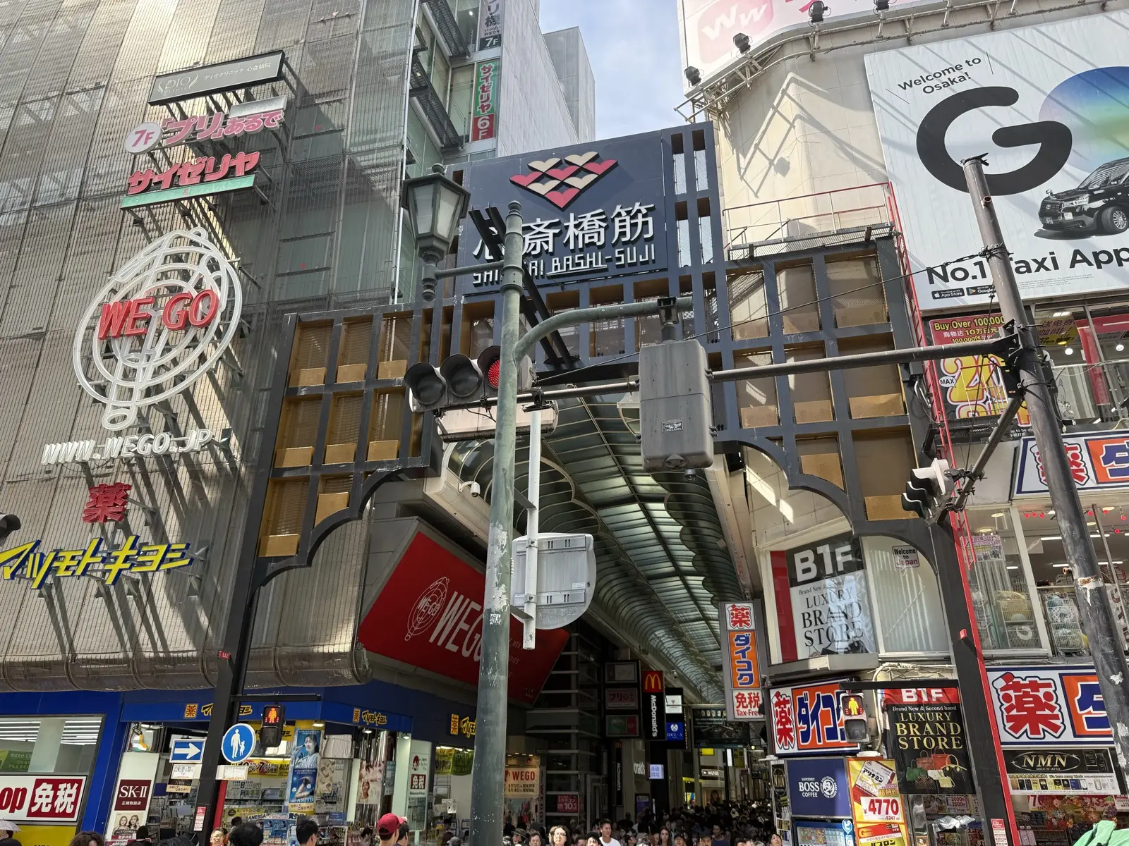 The entrance to Shinsaibashi-suji, a long covered shopping arcade in Osaka, packed with shoppers and lit signboards