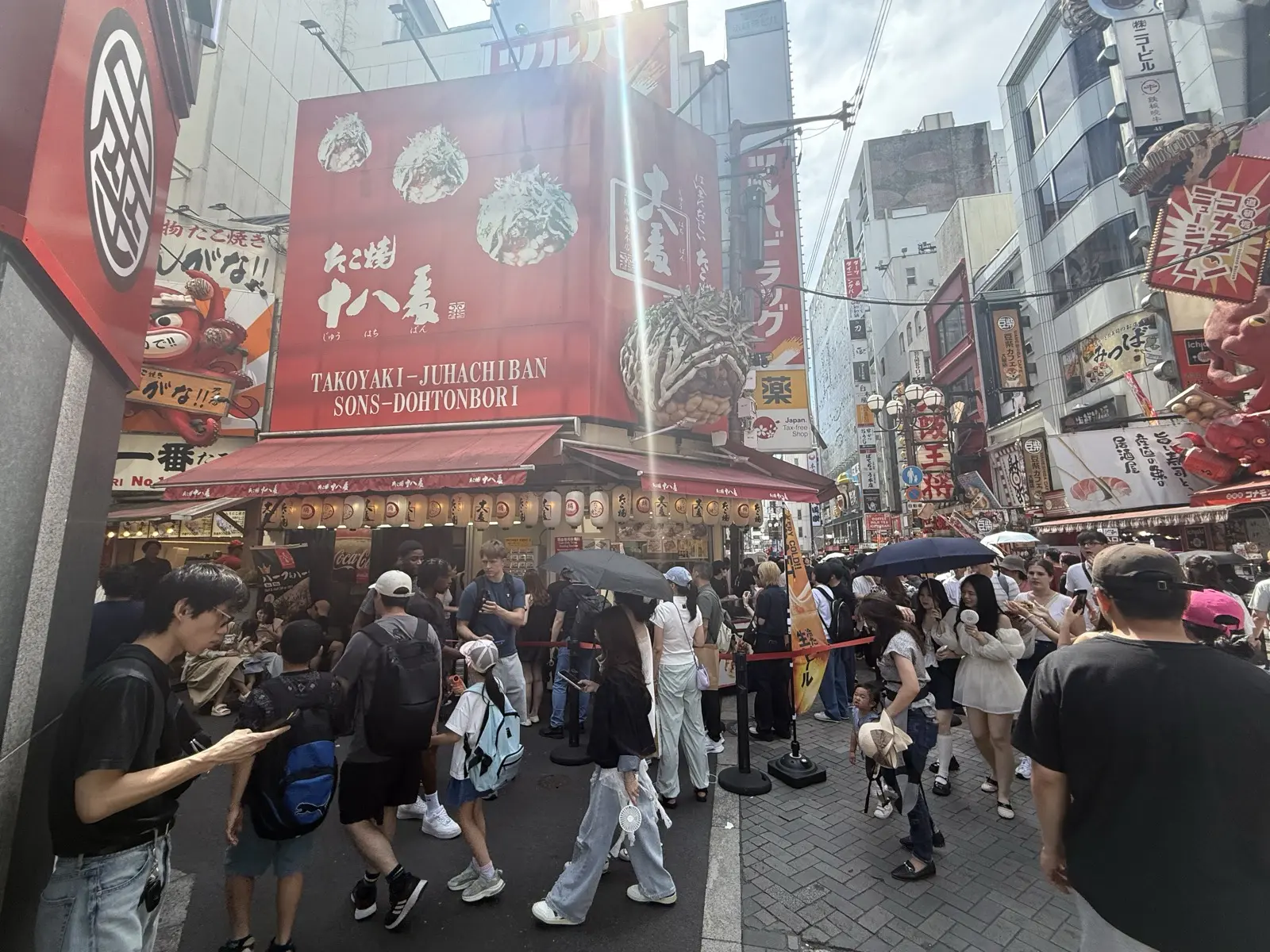 The Takoyaki Juhachiban stand in Dotonbori, Osaka, with a crowd queueing outside under its red signboard