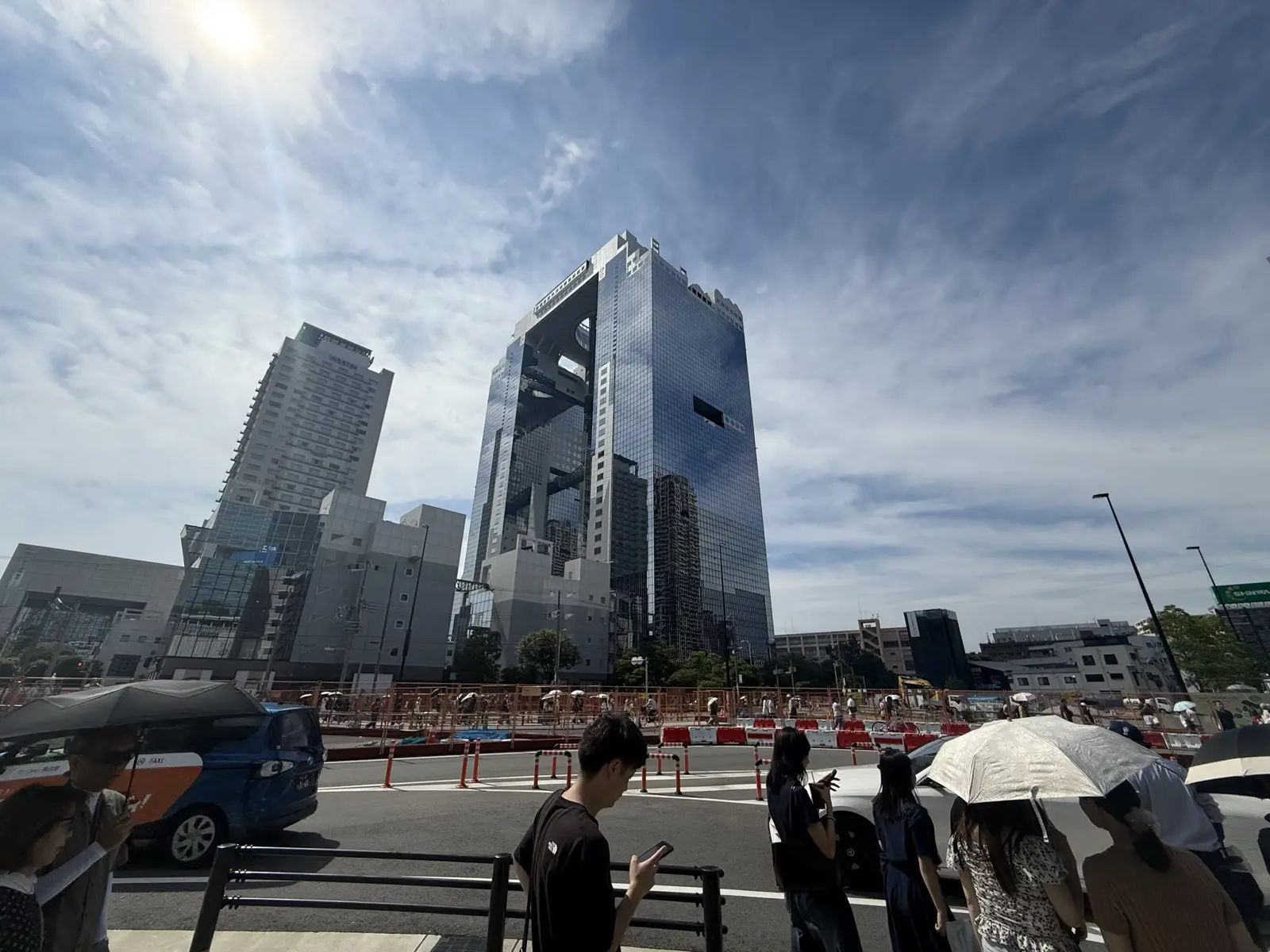 The Umeda Sky Building seen from the ground — twin dark-glass towers linked near the top by the ring-shaped Floating Garden Observatory, against a dramatic sky