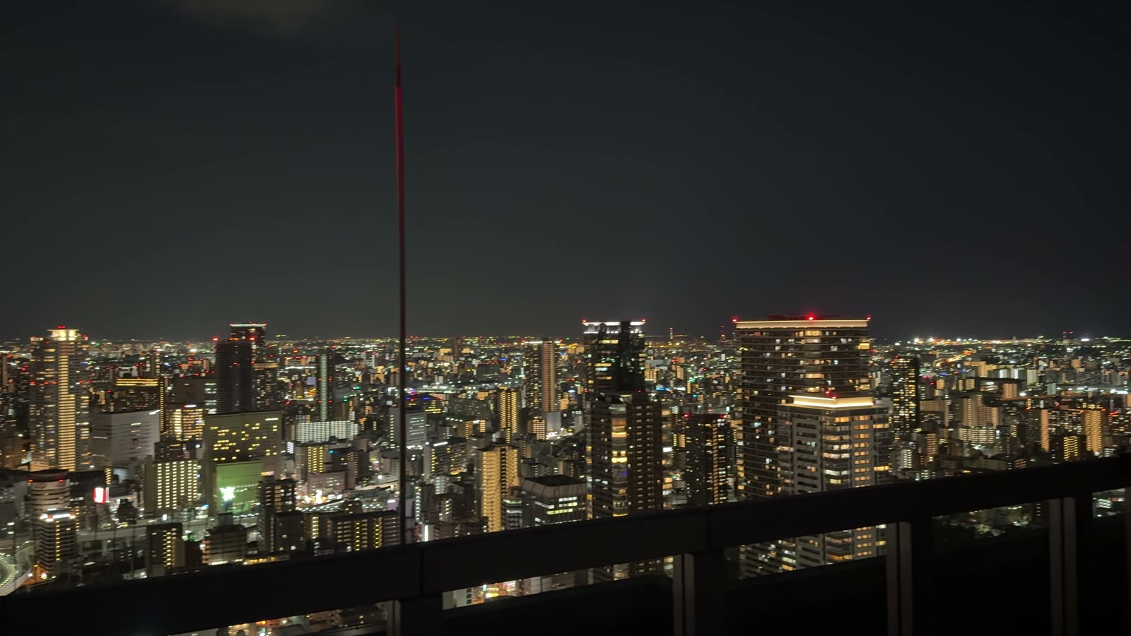 Osaka's skyline and city lights from beside the observatory railing at the top of the Umeda Sky Building