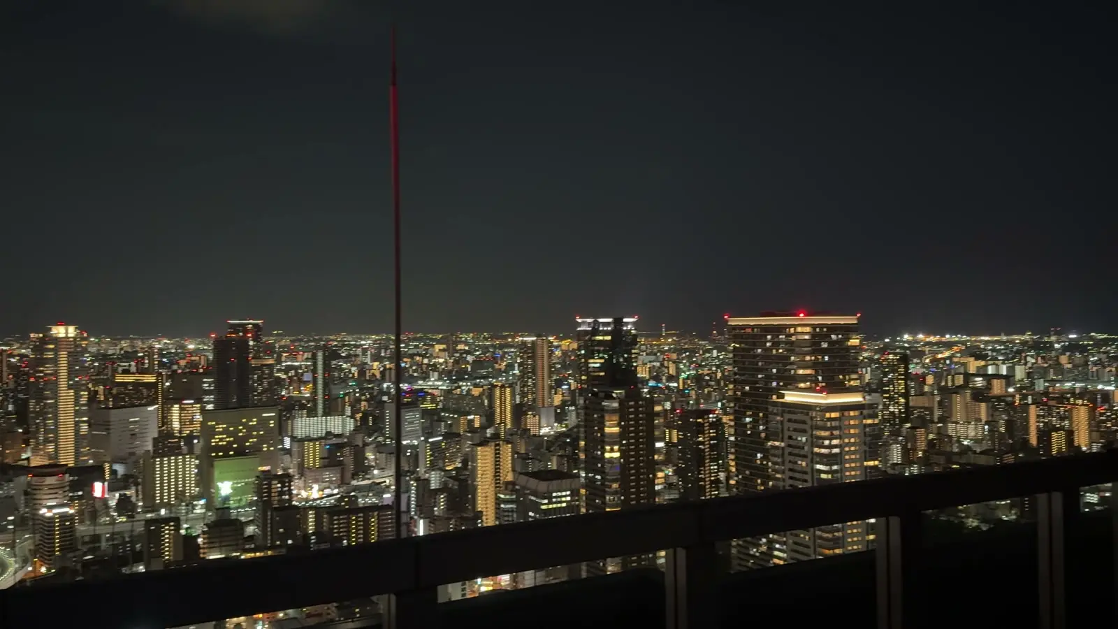 Osaka's skyline and city lights from beside the observatory railing at the top of the Umeda Sky Building