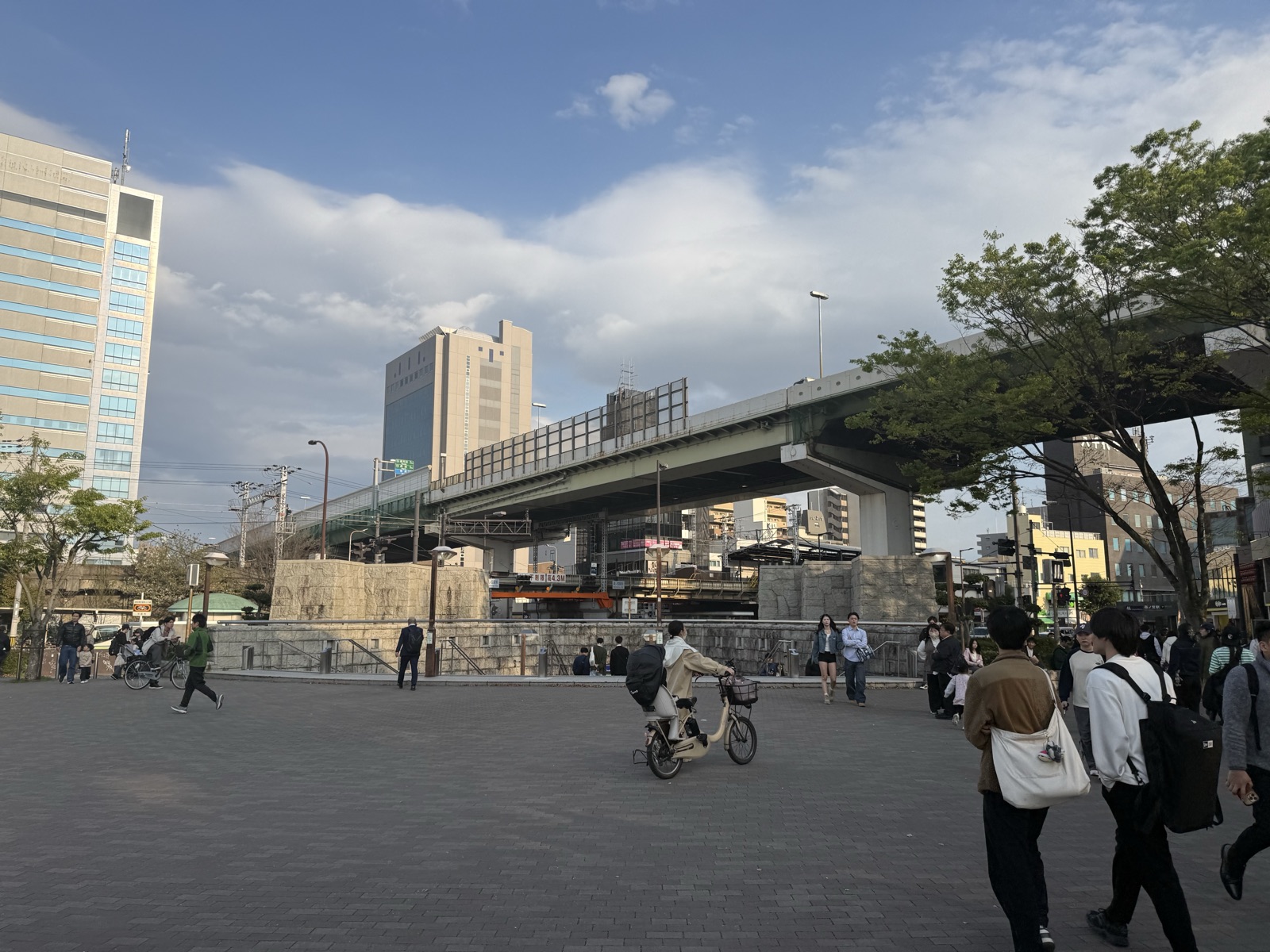 The walk from Osakajokoen Station toward Osaka Castle Park, with an elevated expressway and city buildings, on a clear day